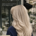 Femme avec des cheveux blonds cendrés et des vagues fluides, portant un style urbain chic.