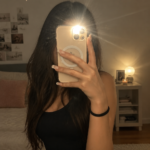 Une brune prenant une photo devant un miroir, mettant en avant sa pose créative.